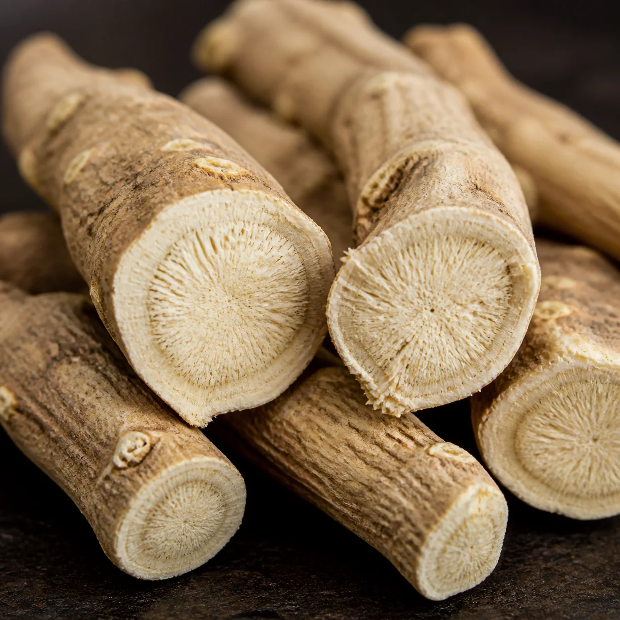 Gros plan de racines d'ashwagandha coupées, avec texture fibreuse beige sur fond naturel sombre